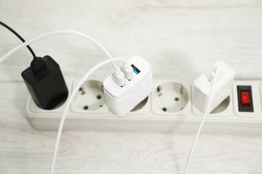 Tahta zemindeki güç şeridine bağlı USB adaptörleri, yakın plan.