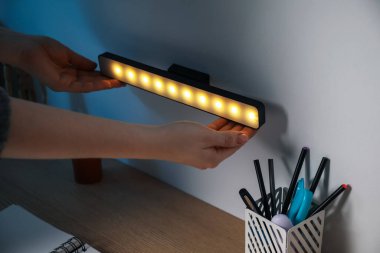 Masanın üstündeki duvara modern LED lamba koyan kadın, yakın plan.