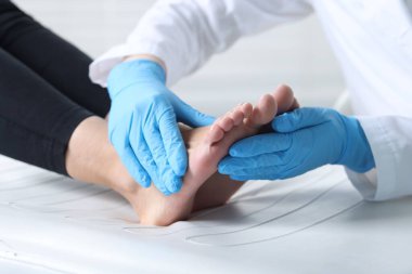 Hastanedeki hastanın ayağını muayene eden doktor, yakın plan.