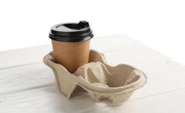 Paper coffee cup in cardboard holder on white wooden table. Space for text