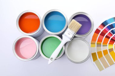 Açık arkaplanda parlak boya kutuları, fırça ve renk paletleri, düz yatış