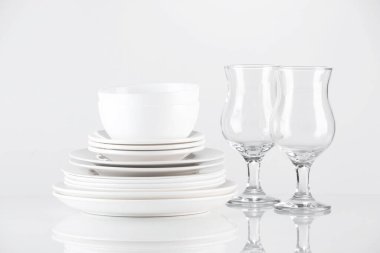 Aydınlık arkaplanda farklı temiz bulaşık takımı ve gözlük