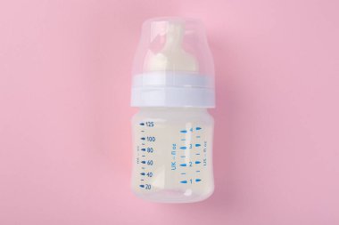 Pembe arka planda sütle beslenme şişesi, üst görünüm