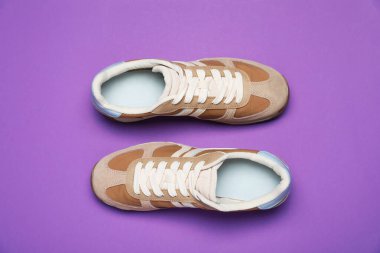 Pair of stylish sneakers on purple background, flat lay. Casual shoes