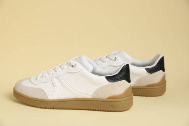 Pair of stylish sneakers on beige background. Casual shoes