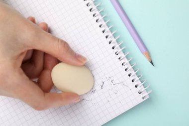 Açık mavi masada silgiye sürtünen bir kadın.