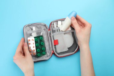 Açık mavi arka planda ilk yardım çantası olan kadın, üst görünümde.