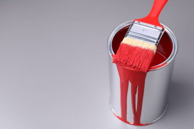 Gri arka planda kırmızı boya ve fırça kutusu, yakın plan. Metin için boşluk