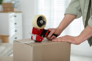 Karton kutuyu bantla kapatan adam içeride, yakın plan.