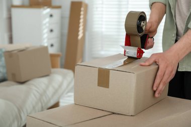 Karton kutuyu bantla kapatan adam içeride, yakın plan.