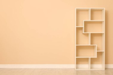 Empty shelving unit near beige wall indoors, space for text