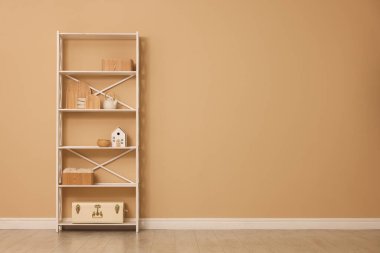 Shelving unit with decor near beige wall indoors, space for text