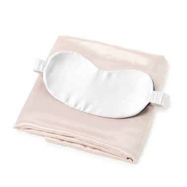 Beyaz arka planda ipek çarşaflar ve uyku maskesi.