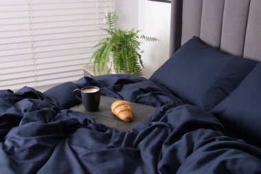 Lezzetli kahve ve kruvasan. Yatakta koyu mavi ipek çarşaflar var.