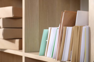 Postanedeki ahşap raflarda farklı kağıt zarflar ve paketler var.