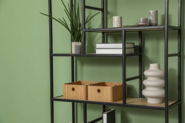 Salon içinde zeytin duvarının yanında farklı dekorasyonu olan ahşap raf ünitesi.