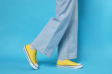 Açık mavi arka planda şık ayakkabılar giyen kadın, yakın plan.
