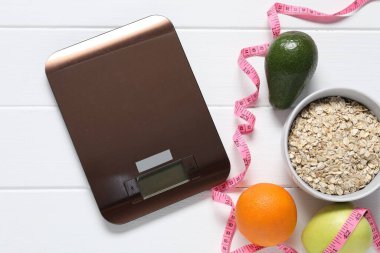 Elektronik mutfak ölçeği, mezura ve beyaz ahşap masa üzerindeki ürünler, düz yatak. Diyet