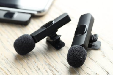 Lavalier mikrofonlar ve ahşap masada kablosuz alıcısı olan akıllı telefon.
