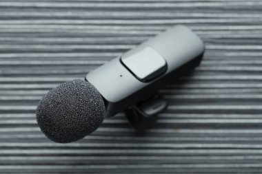 Lavalier mikrofonu siyah ahşap masada, yakın plan.