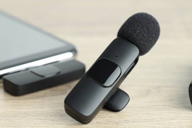 Lavalier mikrofon ve ahşap masada kablosuz alıcısı olan akıllı telefon.