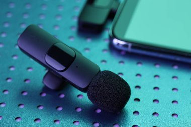 Lavalier mikrofon ve kablosuz alıcısı neon lambalı akıllı telefon, yakın plan.