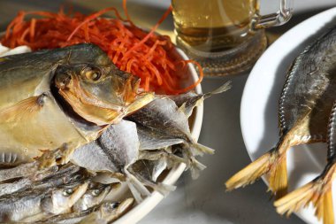 Gri desenli masada farklı kurutulmuş balık ve bira, yakın plan.