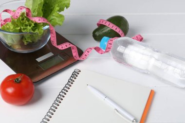 Mutfak pulları, ürünler, su, defter ve mezura beyaz ahşap masa, yakın çekim