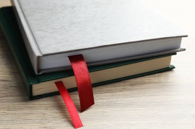 Açık ahşap masa üzerinde kırmızı kurdele yer imleri olan kitaplar, yakın plan