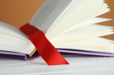 Kahverengi arkaplana karşı beyaz ahşap masa üzerinde kırmızı kurdele yer imi olan kitabı aç, kapat