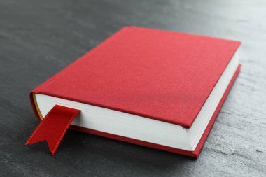 Koyu desenli masa üzerinde kırmızı kurdele yer imi olan kitap, yakın plan.