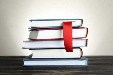 Açık gri arkaplan, yakın plan, ahşap masa üzerinde kırmızı kurdele yer imi ve renkli olanlar kitap