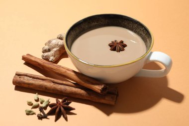 Fincanda Aromatik Masala çayı ve bej arka planda baharatlar, yakın plan.
