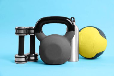Açık mavi arka planda Kettlebell ve diğer spor ekipmanları