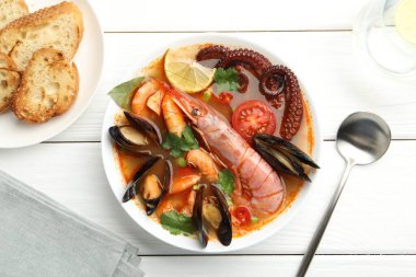 Lezzetli deniz ürünleri çorbası beyaz ahşap masada servis edilir.