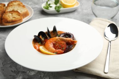 Gri desenli masada servis edilen lezzetli deniz ürünleri çorbası, yakın plan.