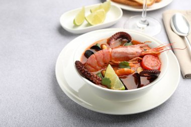 Açık gri masada servis edilen lezzetli deniz ürünleri çorbası, yakın plan. Metin için boşluk