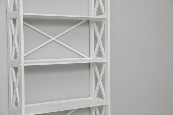 Empty shelving unit near light grey wall