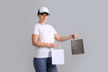 Gri arka planda damgalamak için boş eşyaları olan bir kadın. Tasarım için model