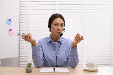 Kulaklıkla hoparlör açık oturulan masada webinar, web kamerasından görüntü