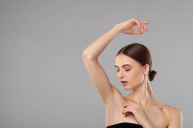 Gri arkaplandaki epilasyondan sonra pürüzsüz cilt gösteren genç kadın, metin için boşluk