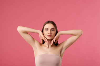 Young woman showing smooth skin after epilation on pink background