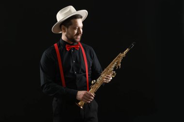 Siyah arka planda soprano saksafonu olan profesyonel bir müzisyen.