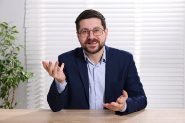 Gülümseyen çevrimiçi hoparlör. İçerideki masada web kamerasından görüntüsü olan webinar.