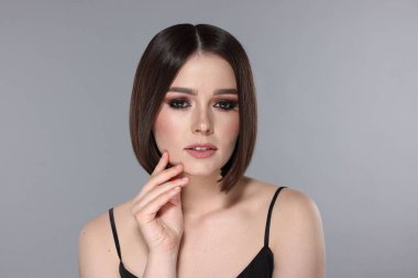 Açık gri arka planda muhteşem düz saçlı güzel bir genç kadının portresi.