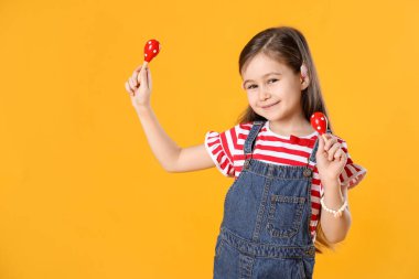 Sarı arka planda oyuncak marakas oynayan tatlı kız.