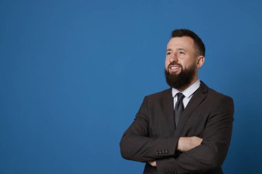 Mavi arka planda takım elbiseli yakışıklı sakallı adam. Metin için boşluk