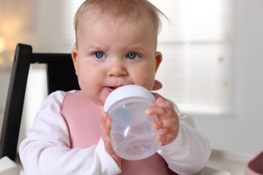 Evde şişe ile beslenme sandalyesinde sevimli küçük bebek