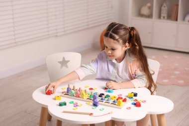 Motor beceri geliştirme. Küçük kız matematik oyunuyla oynuyor Beyaz masada sayıları avlıyor