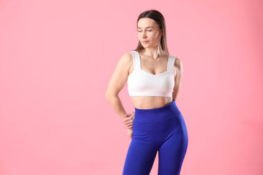 Spor kıyafetli kadın pembe arka planda poz veriyor, metin için boşluk var.